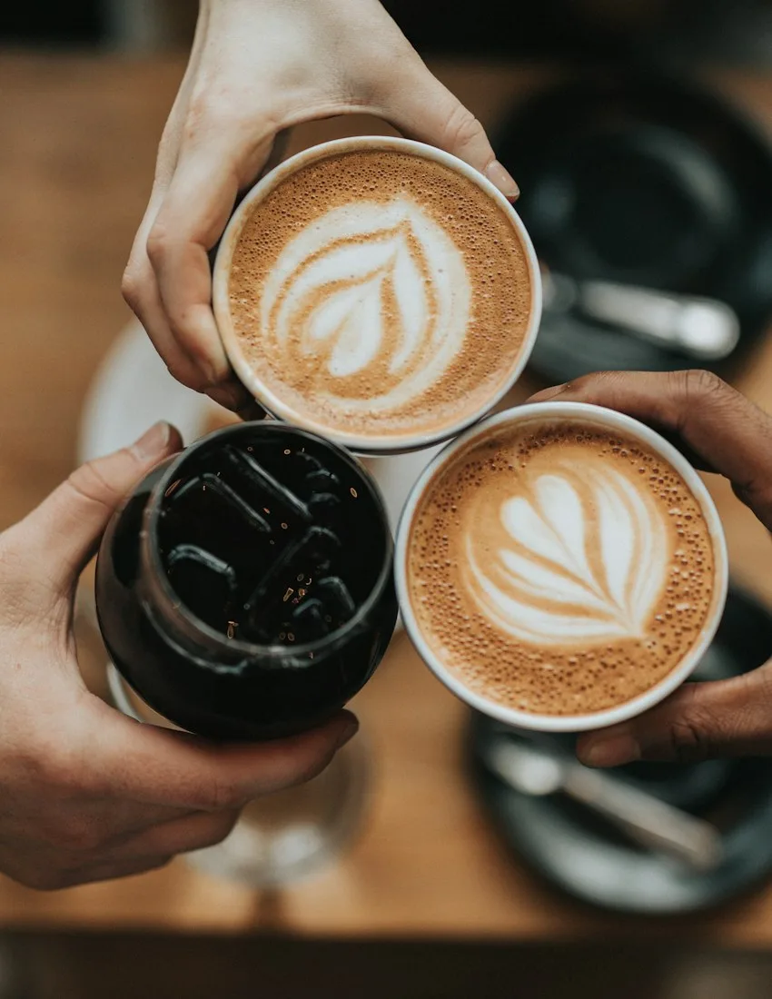 Friends holding their coffees together at a café
